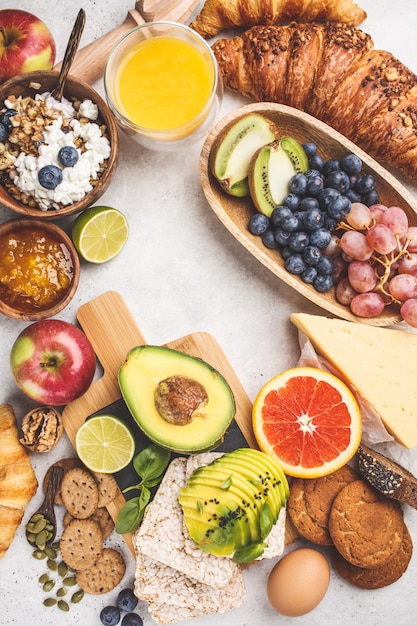 Healthy balanced breakfast on white background. muesli, juice, croissants, cheese, biscuits and fruit, top view. Premium Photo