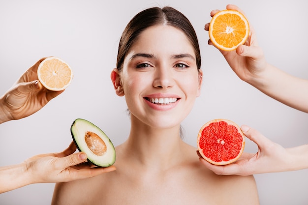 Healthy beautiful radiant skin of woman without makeup. portrait of girl smiling against wall of fruits. Free Photo