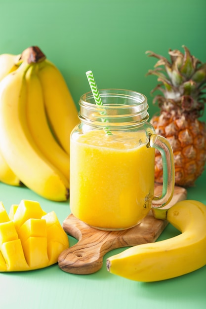 Premium Photo | Healthy yellow smoothie with mango pineapple banana in ...