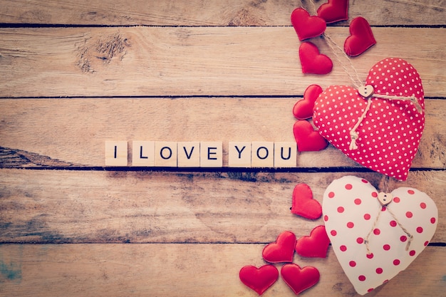 Heart fabric frame and wooden text i love you on wooden table background. Premium Photo