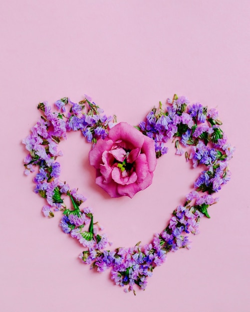 ピンクの背景にラベンダーとピンクの花で作られた心 無料の写真
