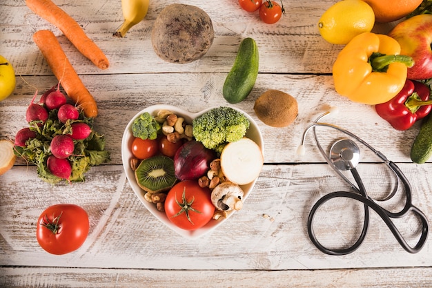 Heart shape container with healthy vegetables near stethoscope Free Photo