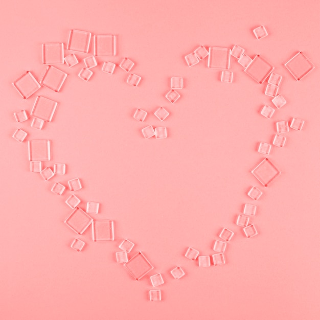 Heart shape made with different type of transparent cubes on coral background Free Photo