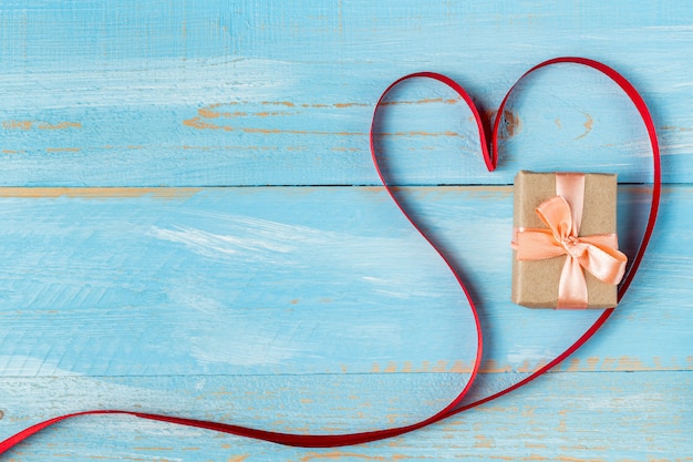 Heart shaped ribbon and gift box on a blue wooden table. valentine's day gift Premium Photo