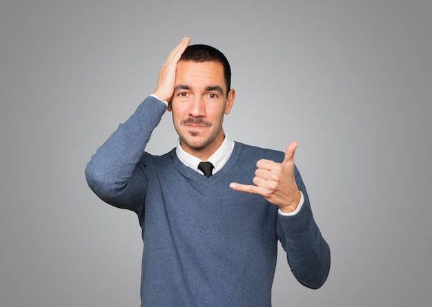 Premium Photo | Hesitant young man making a gesture of calling with the ...