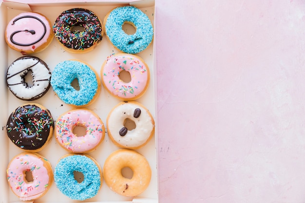 Download Free Photo Fresh Donuts On Chopping Board Near Package Over Pink Background