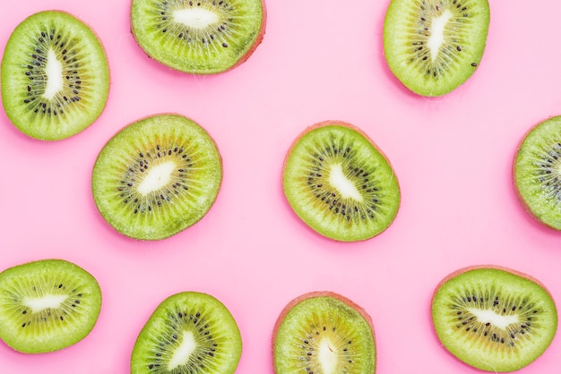 High angle view of kiwi fruit slices on pink background 