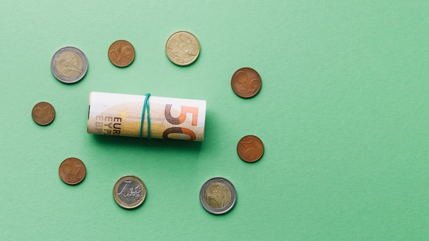 High angle view of rolled up euro bank note with coins on green background  Photo | Free Download