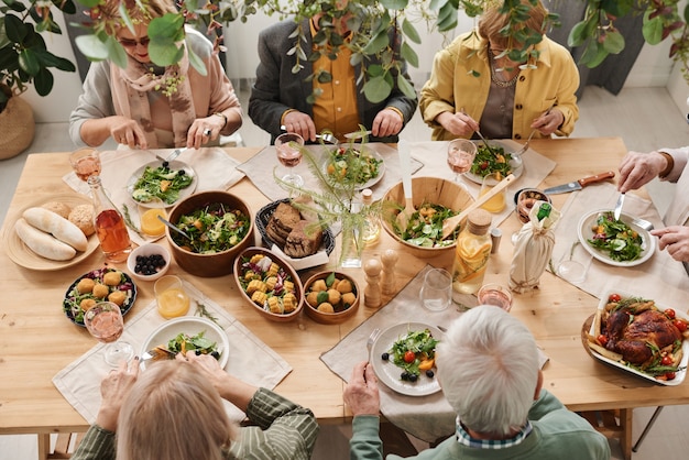 Premium Photo | High angle view of people sitting at dining table with ...