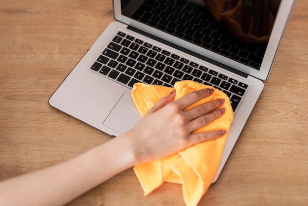 Free Photo | High angle of woman cleaning laptop with cloth