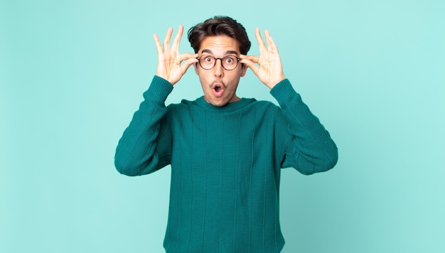 Premium Photo Hispanic Handsome Man Feeling Shocked Amazed And Surprised Holding Glasses