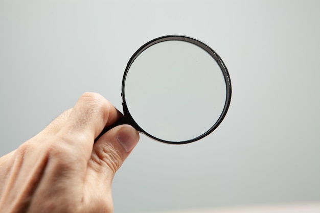 Premium Photo | Holding a magnifying glass on a gray background. search