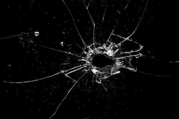 Premium Photo | Hole in the glass with cracks isolated on a black ...