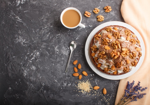 Homemade cake with milk cream, cocoa, almond, hazelnut with orange textile and a cup of coffee. top view, copy space. Premium Photo