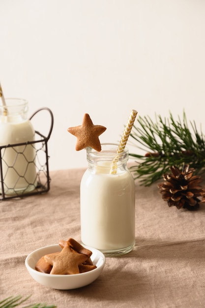 Premium Photo | Homemade cookies in shape of star and milk for santa claus  and christmas tree on table. close up.