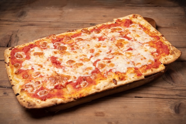 Premium Photo | Homemade square pizza with cheese on wooden table close up