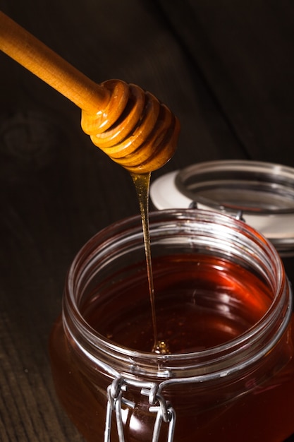 Premium Photo | Honey drip in jar on the table