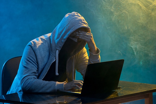 Hacker komputer berkerudung mencuri informasi dengan laptop Free Photo