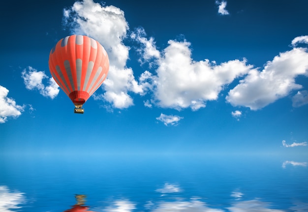 Premium Photo | Hot air balloon in blue sky over water surface