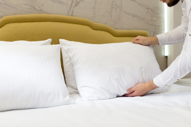 Premium Photo | Hotel staff setting up pillow on bed