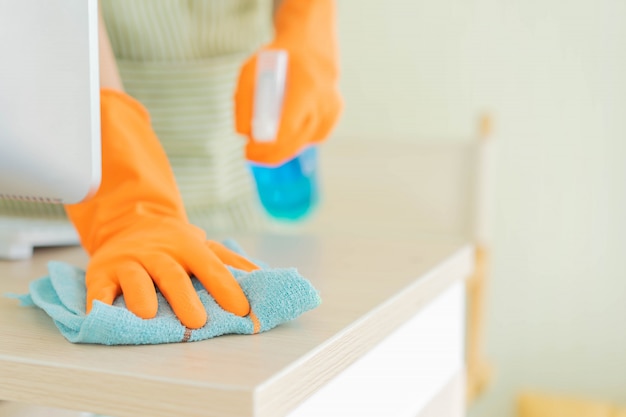 House keeper using microfiber fabric swipe on wooden table to cleaning desktop table Premium Photo