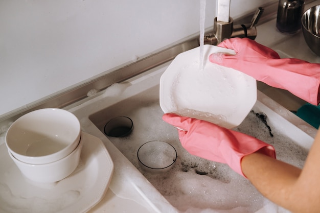 Premium Photo Housewife girl in pink gloves washes dishes by hand