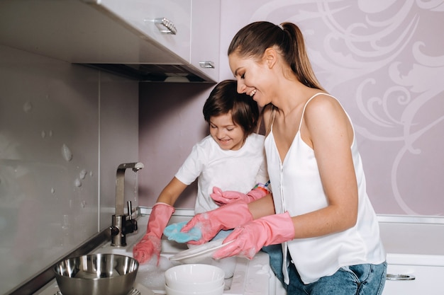 Premium Photo Housewife Mom In Pink Gloves Washes Dishes With Her Son