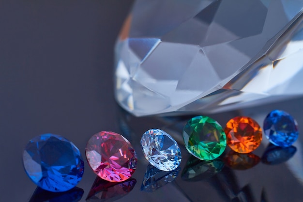 Huge diamond and several chic crystals on a deep black mirror surface, shimmer and sparkle Premium Photo