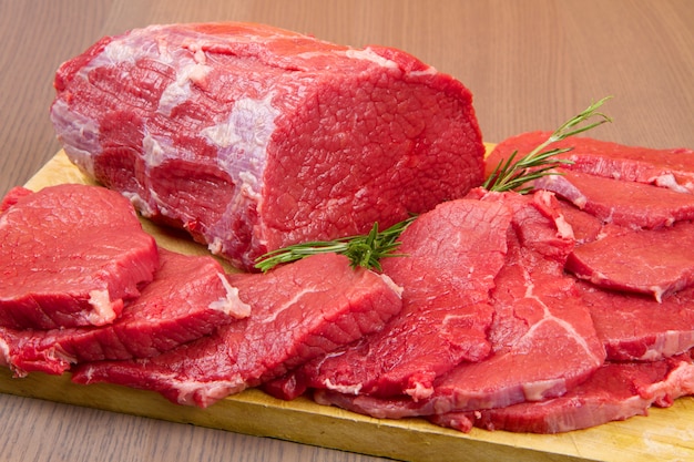 Huge red meat chunk and steak on wood table Premium Photo