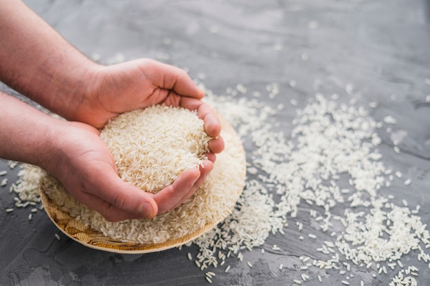 Human hands picking rice from wooden plate over concrete background Free Photo