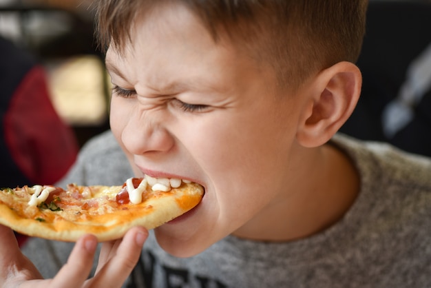 Hungry teenager eats pizza at pizzeria | Premium Photo