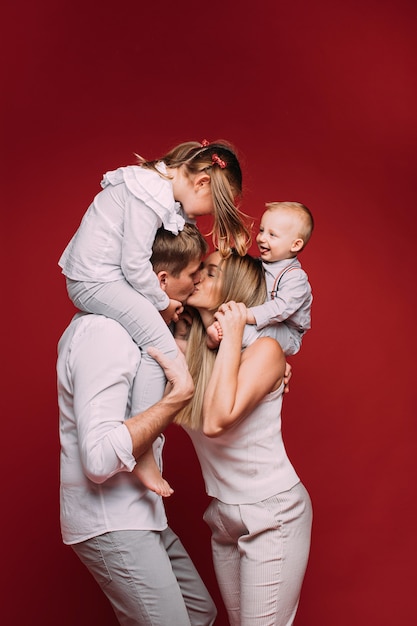 Free Photo Husband and wife kissing with children on shoulders. picture