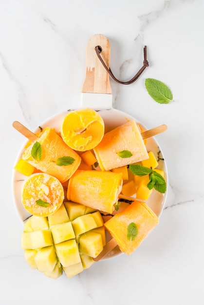 Premium Photo Ice Cream Popsicles Organic Dietary Foods Desserts Frozen Mango Smoothie With Mint Leaves And Fresh Mango Fruit On Plate On White Marble Table Top View