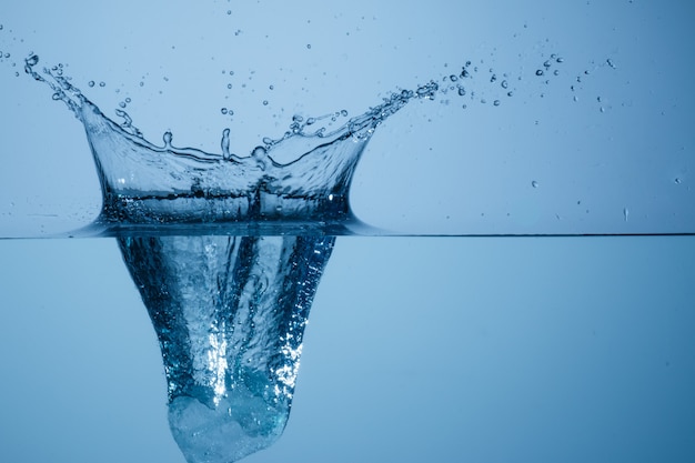 Premium Photo | Ice cube thrown into water container and photographed ...