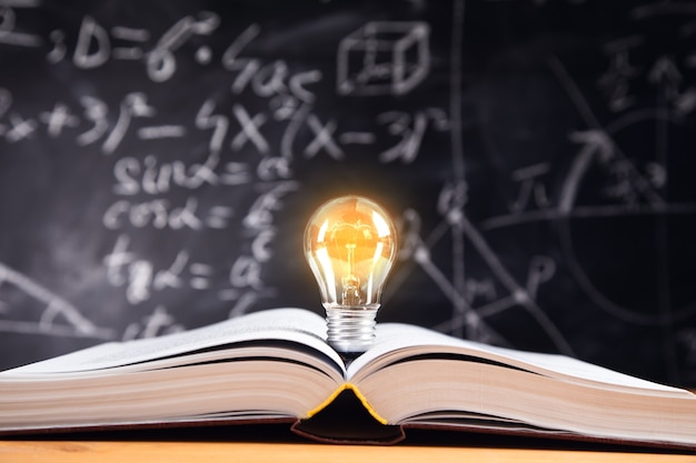 Premium Photo | Idea concept, light bulb on book with blackboard