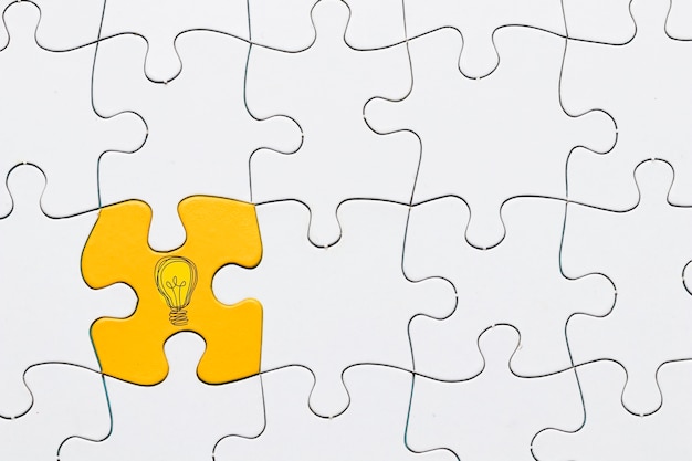 Idea icon on yellow puzzle piece connected with white grid puzzle backdrop Free Photo
