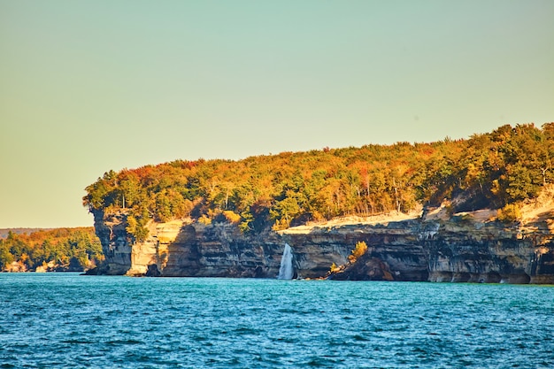 Premium Photo | Image of pictured rocks with distant waterfall pouring ...