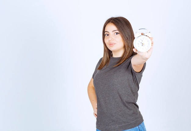 Free Photo | Image of a young nice woman model showing an alarm clock.