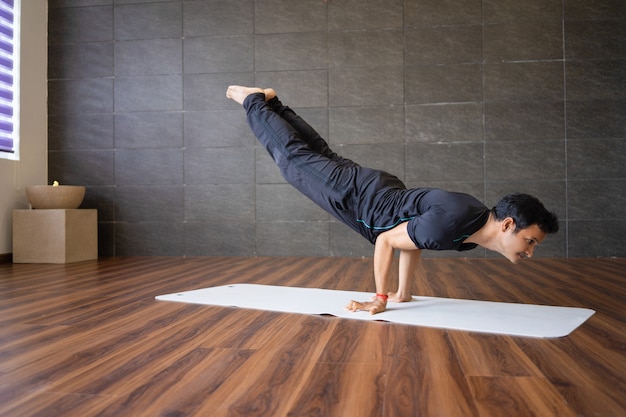 Indian yogi doing advanced hand stand yoga pose in gym ...