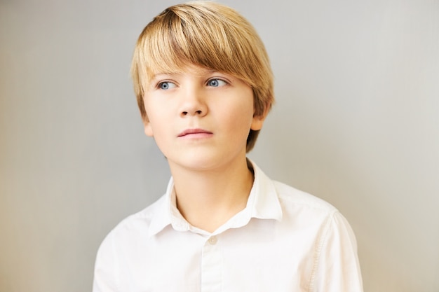 Free Photo Isolated Portrait Of Amazed Caucasian Boy With Fringe And Blue Eyes Looking Away With Mysterious Pensive Expression Deep In Thoughts Pondering Having Idea Or Making Plan Posing At Blank