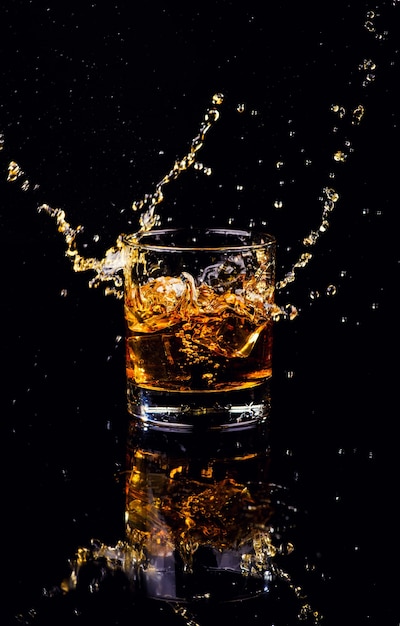 黒の背景にスプラッシュとウイスキーの分離ショット プレミアム写真