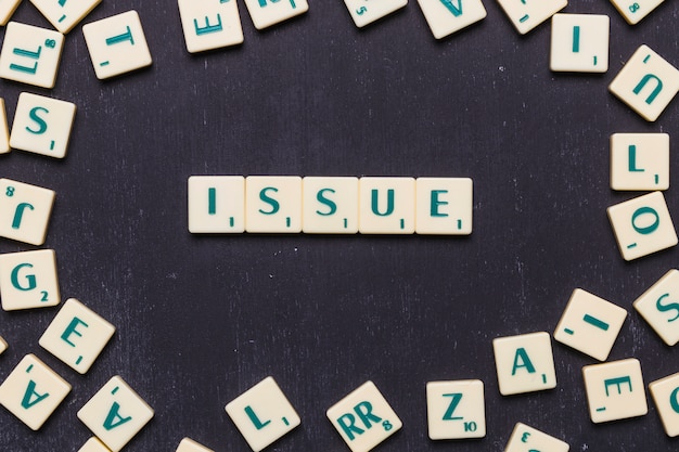 Issue scrabble letters arranged over black backdrop Free Photo