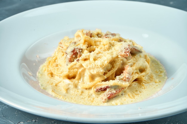 白い皿にホワイトソース パルメザンチーズ ベーコンのイタリアンパスタカルボナーラ 自家製スパゲッティ プレミアム写真