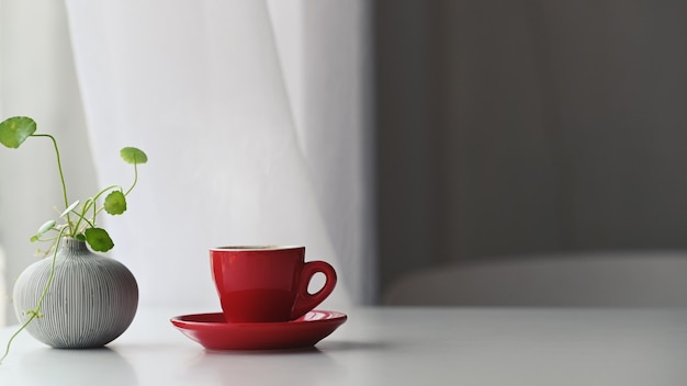 Premium Photo | Ivy in vase and red ceramic coffee cup with coasters ...