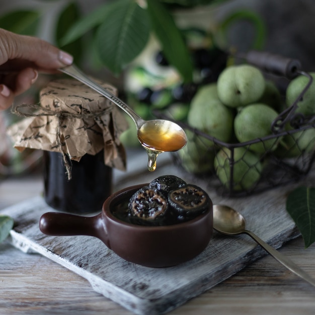 Premium Photo Jar of walnut jam on a wooden table and a group of green walnuts.