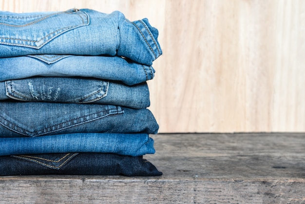 Jeans stacked on a wooden table | Premium Photo
