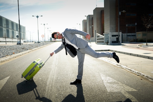 Joyful businessman playing with his suitcase Free Photo