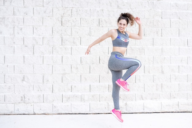 Joyful Sporty Woman Jumping Near Wall Free Photo