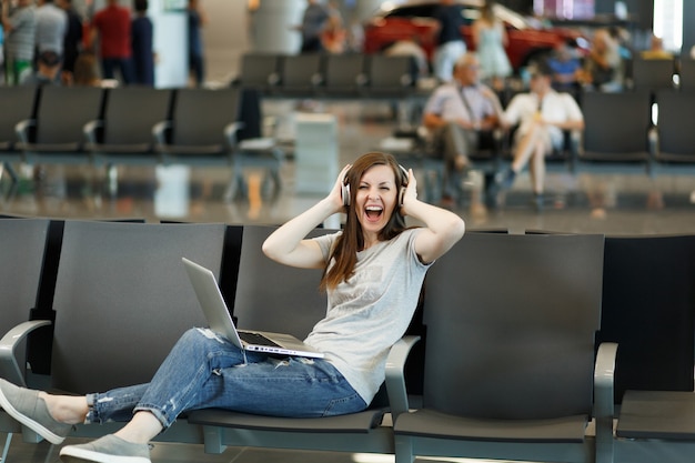 Free Photo Joyful Traveler Tourist Woman With Headphones Listening Music Working On Laptop 