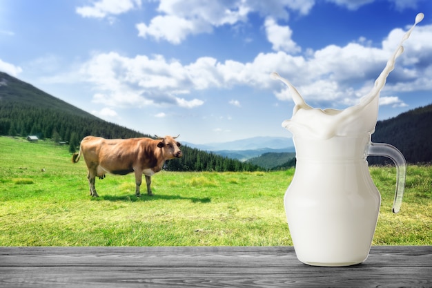 Premium Photo | Jug of milk with splash with brown cow in mountains